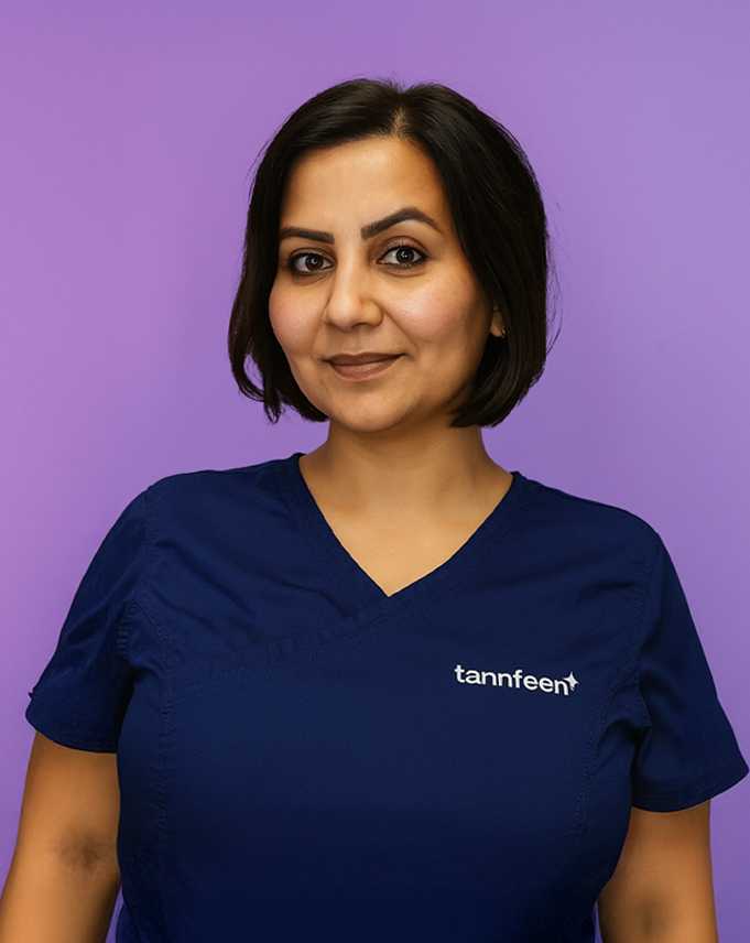 Portrett av en kvinne med kort mørk hår i navyblå scrubs, med logoen «tannfeen» på venstre side, foran en lilla bakgrunn og med et vennlig smil.